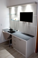 Escritório com painel para TV, prateleiras de vidro e iluminação com spots.