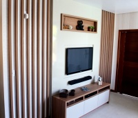 Home com acabamento laqueado e detalhes laterias com sarrafos e tons amadeirados